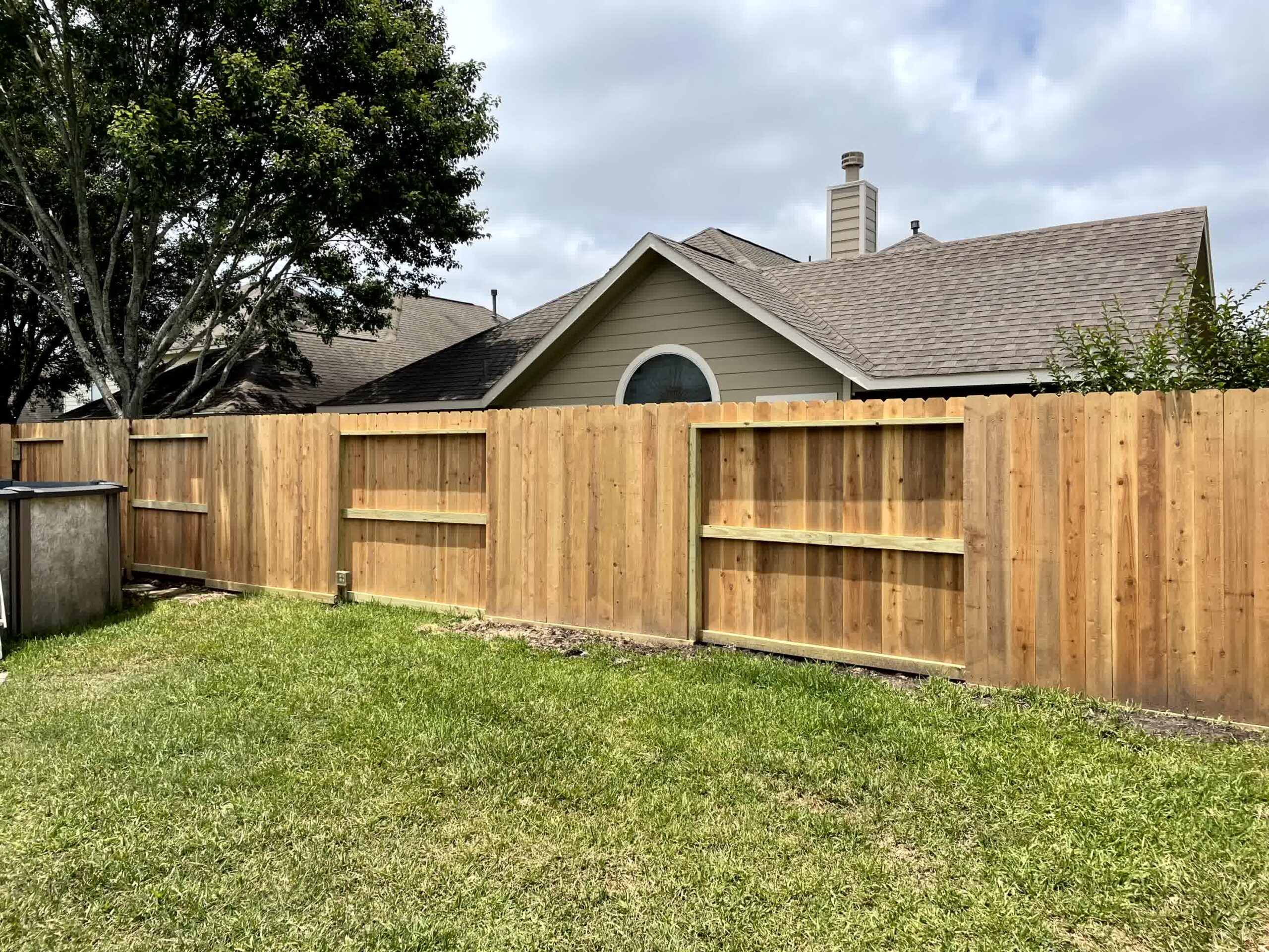 cut n edge property management humble Which Wood Is Best for Your Wooden Fence Discover the 3 Best Wood Types for Fences scaled -Cut'N Edge Property Management A wooden fence with grass in front of it.