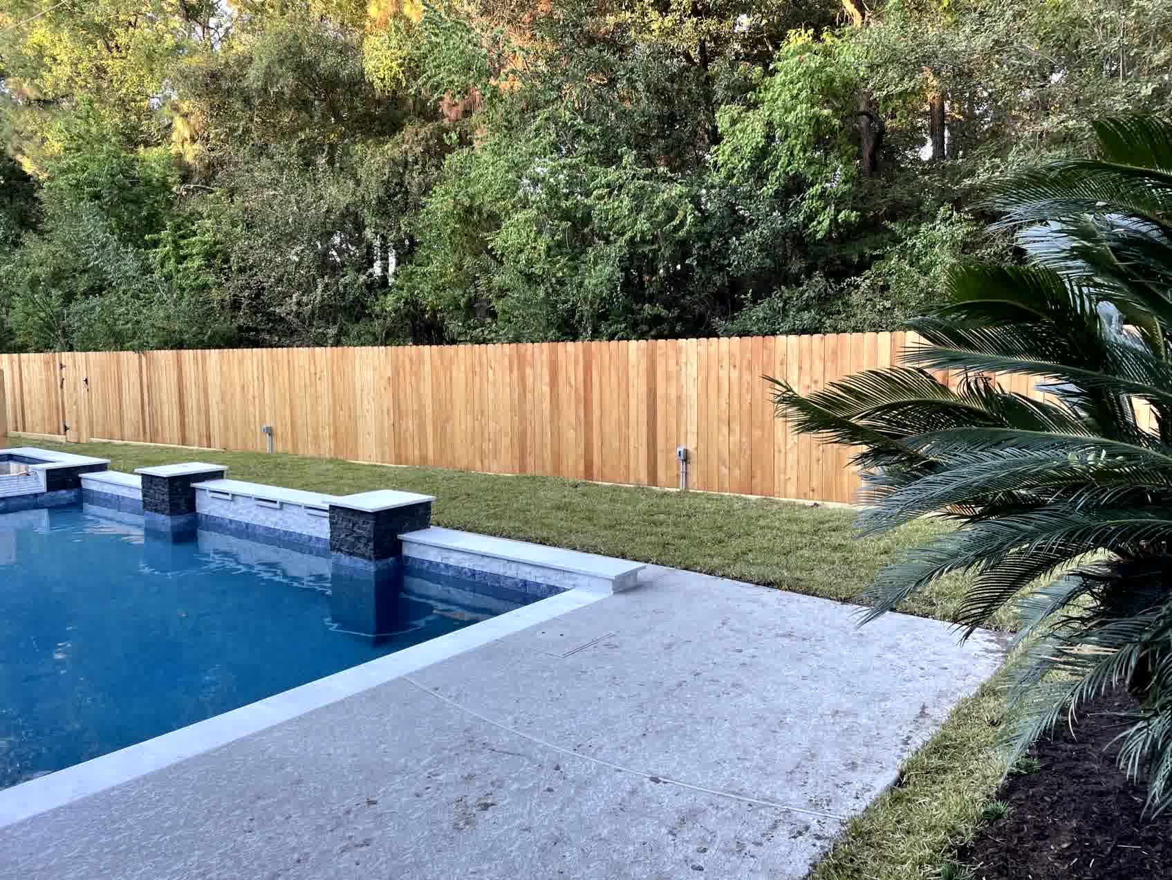 A strong fence around a backyard that has a pool.
